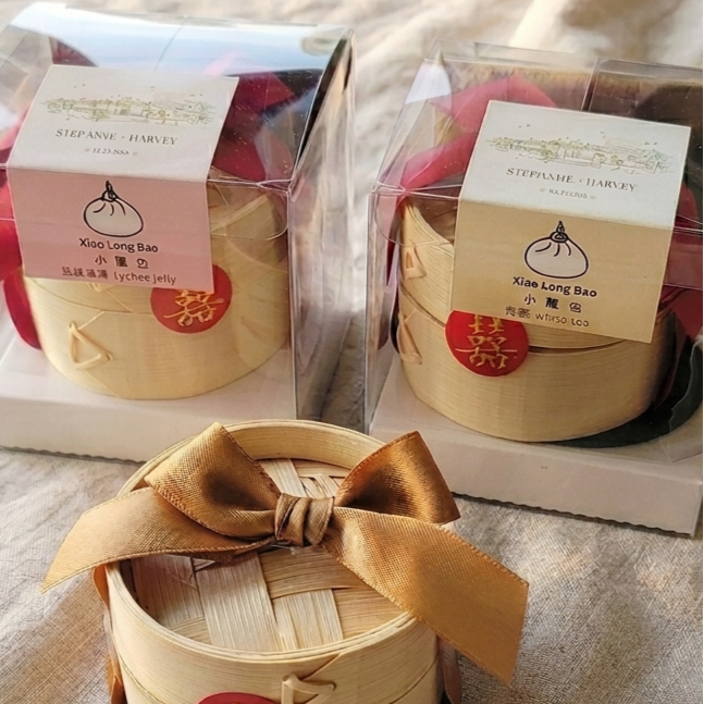 Bamboo steamer basket with a bow and two containers labeled 'Xiao Long Bao' on a light background. Custom label and sticker for custom gifting option. perfect for wedding favors or corporate events gifts
